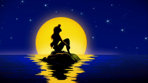 Mermaid sitting on tiny island in full moon gazing up at the sky gif