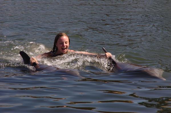 Bethany being pulled through water by two dolphins
