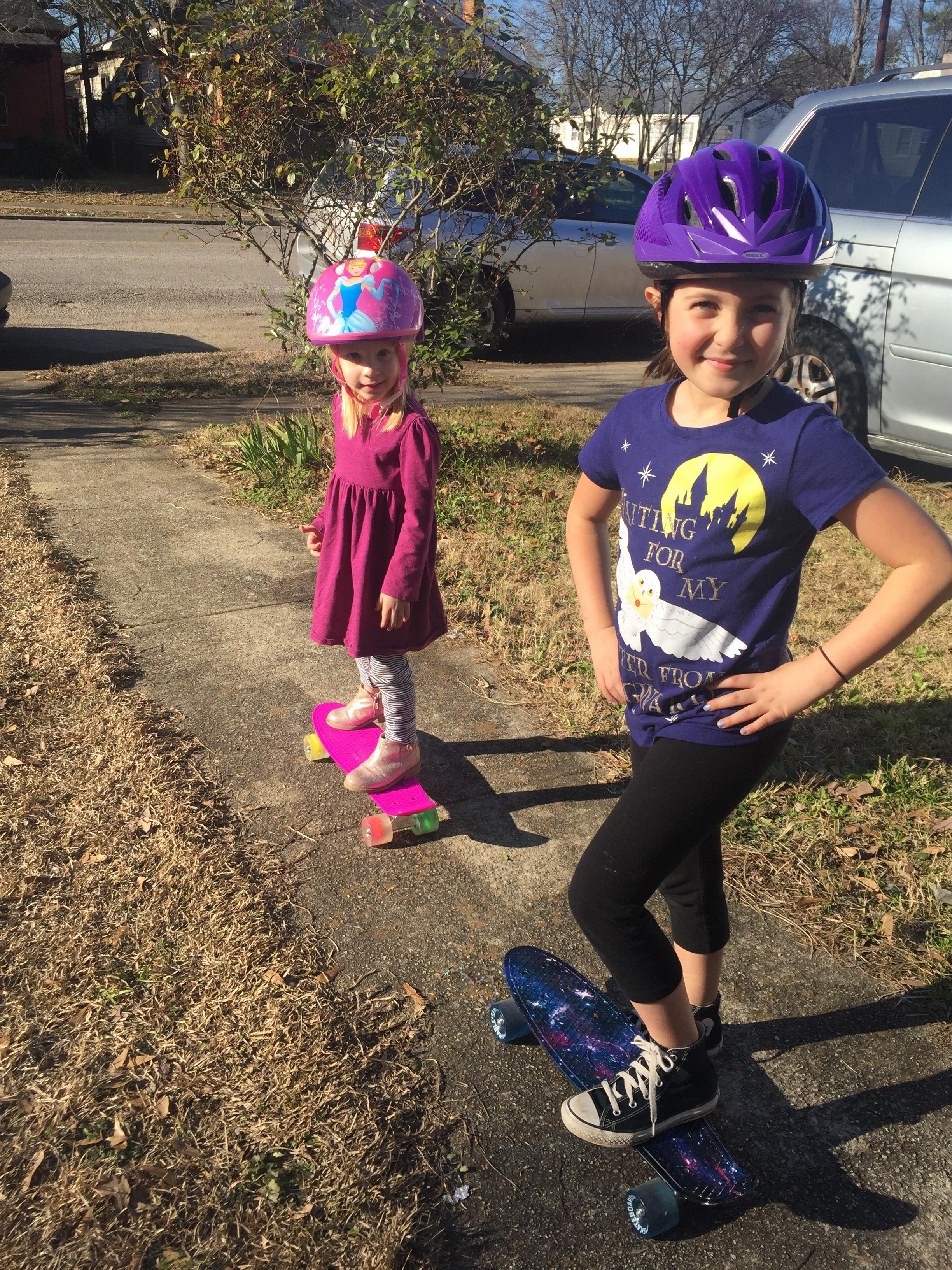Reagan and Aeryn on skateboards in front of house